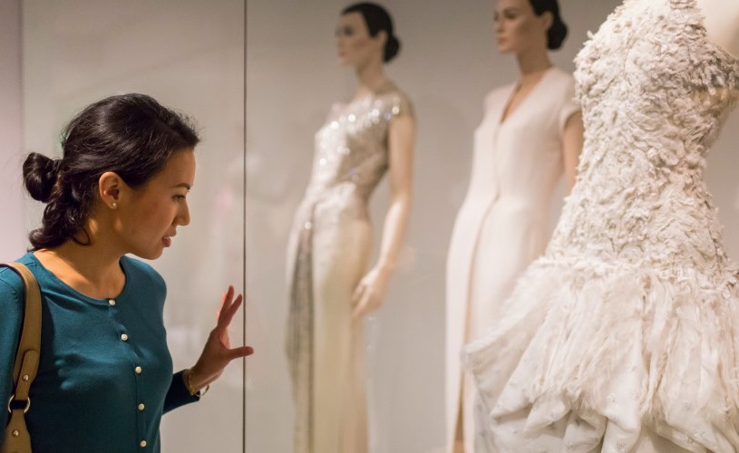 Woman looking at dress on display at Fashion Museum Bath